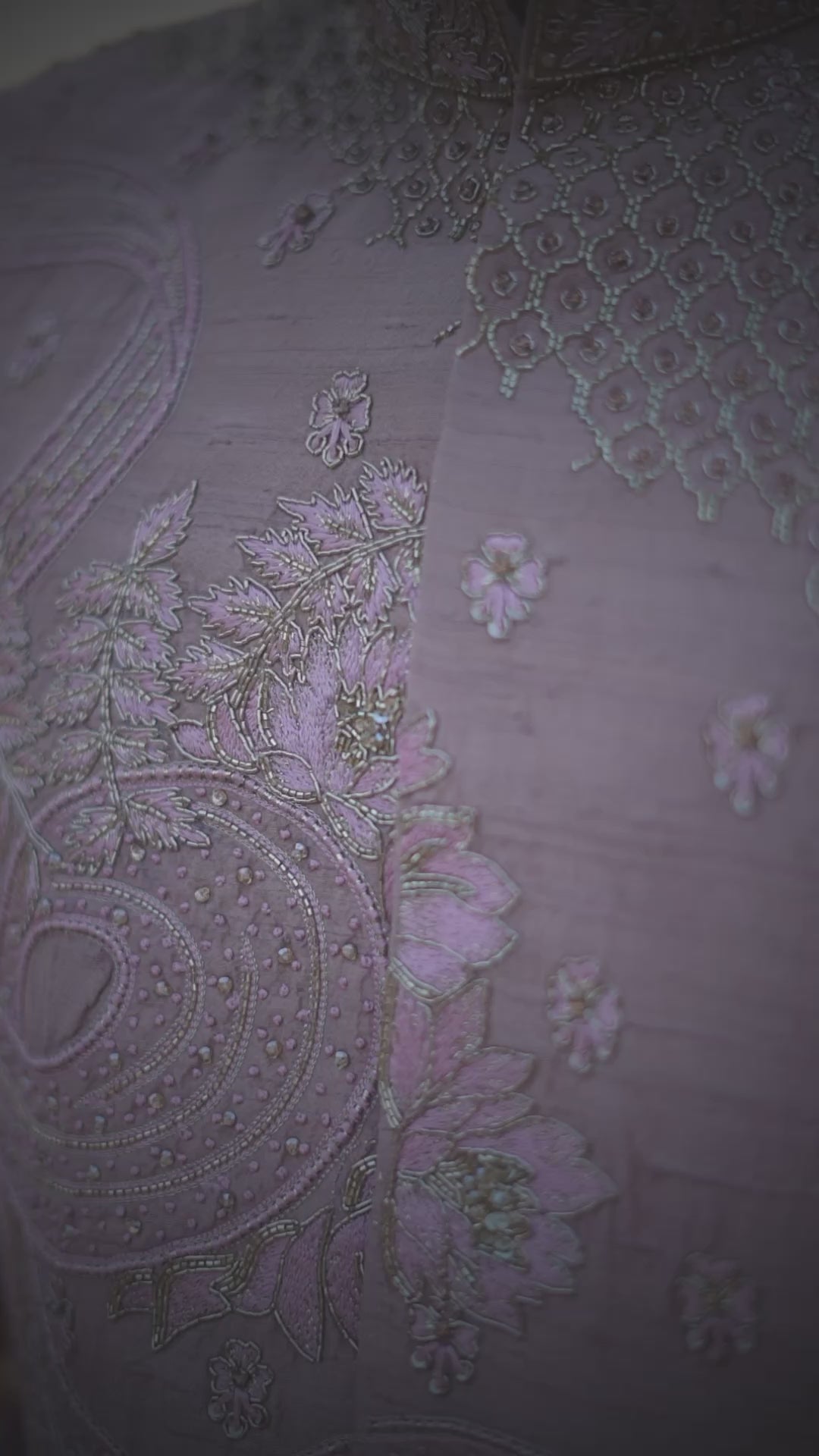 A man wearing a traditional Sherwani with premium silk dhoti and khandwa, featuring intricate embroidery and a pink tint.